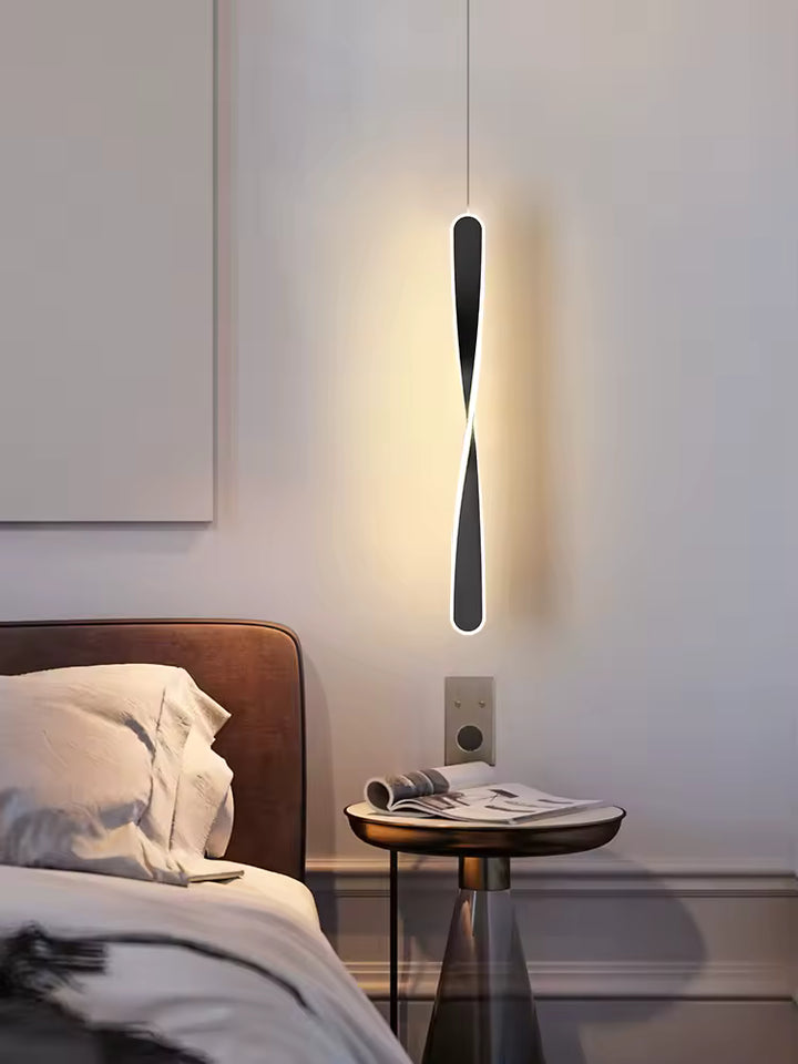 Près du chevet, une suspension noire torsadée au contour lumineux dessine une silhouette moderne et sculpturale