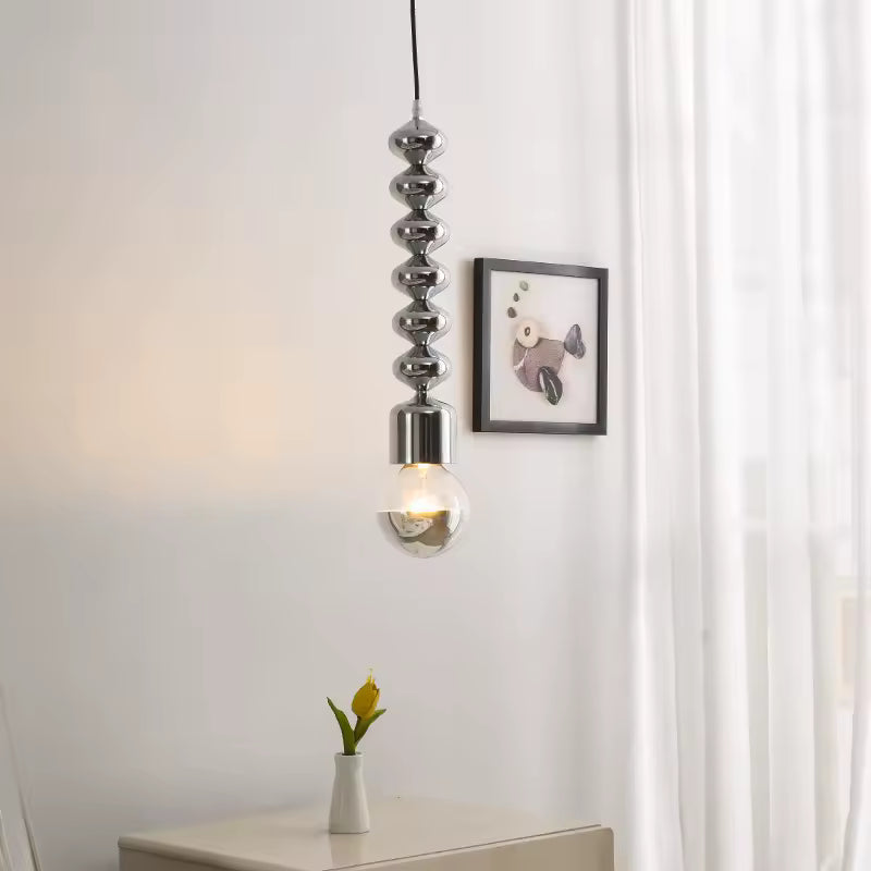 Dans un décor épuré, cette suspension totem chromée à ampoule métallisée affiche un style contemporain et sculptural