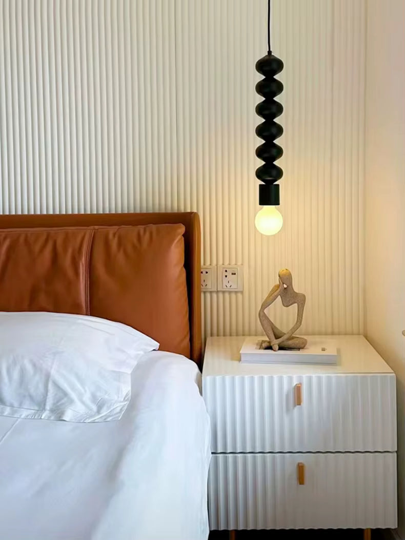 Près du lit, cette suspension totem noire apporte une touche sculpturale, contemporaine et minimaliste