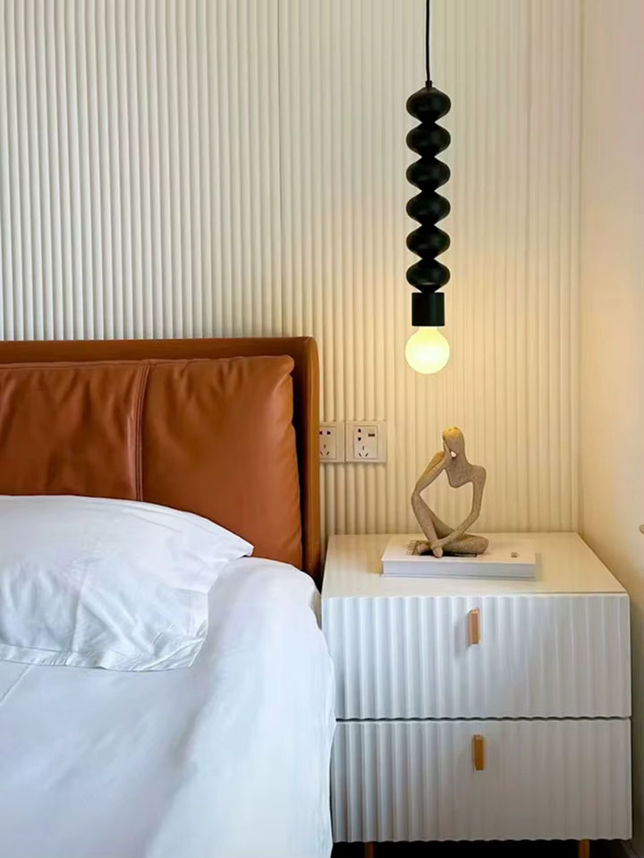 Près du lit, cette suspension totem noire apporte une touche sculpturale, contemporaine et minimaliste