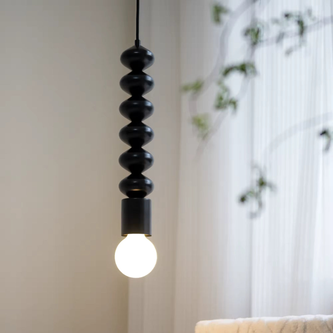 Ligne sculpturale noire et globe lumineux composent une suspension contemporaine au style minimaliste et graphique