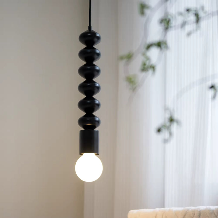 Ligne sculpturale noire et globe lumineux composent une suspension contemporaine au style minimaliste et graphique