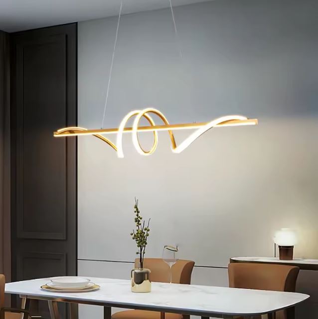 Suspension tourbillon dorée au-dessus d’une table design, parfaite pour une salle à manger chic et contemporaine.