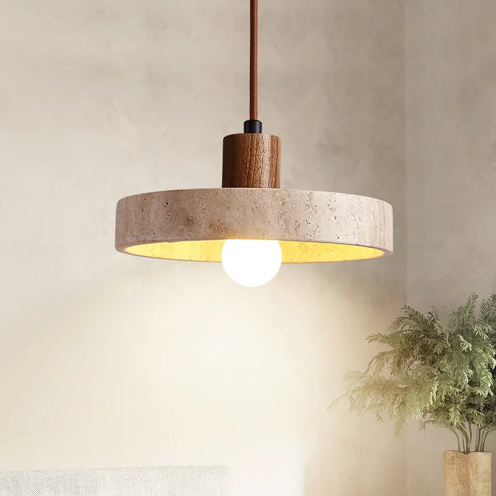 Suspension design en travertin et bois allumée, présentée de côté dans un intérieur lumineux au style naturel et épuré.