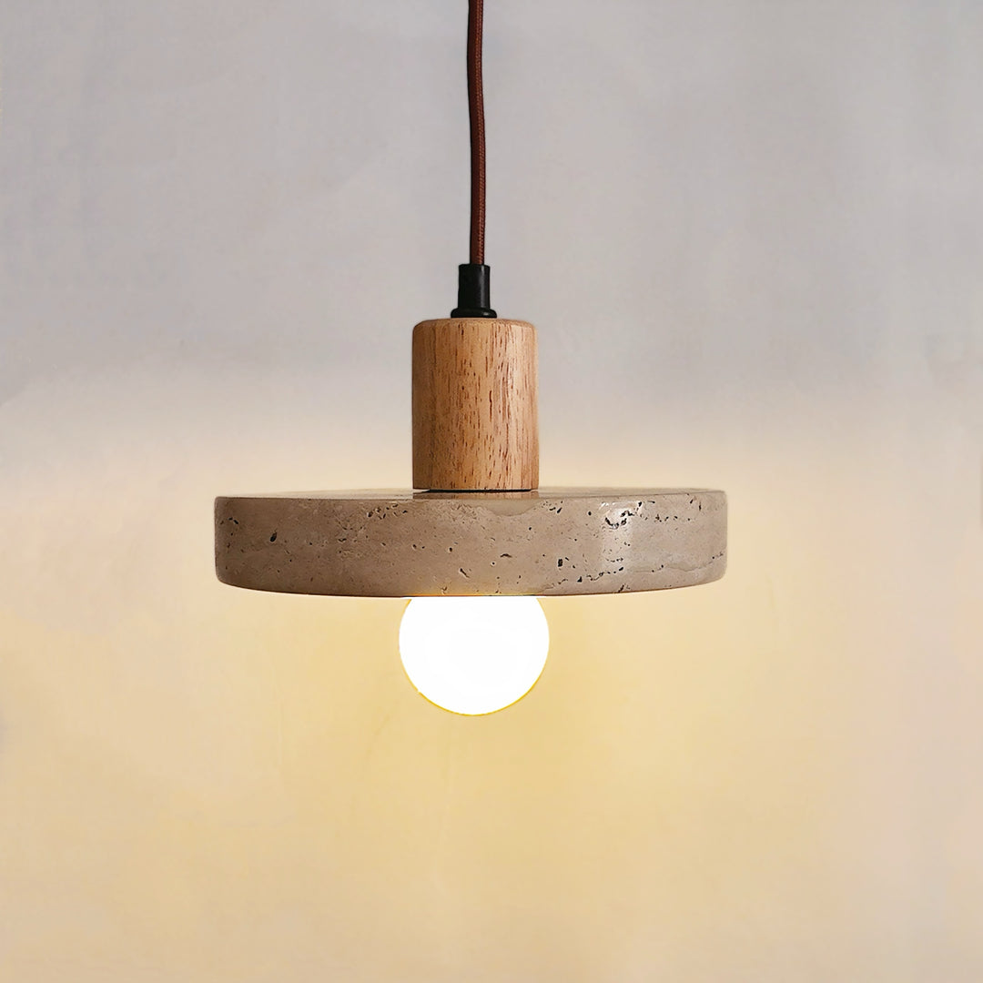 Vue rapprochée d'une suspension lumineuse en travertin et bois clair avec ampoule décorative sur fond neutre.