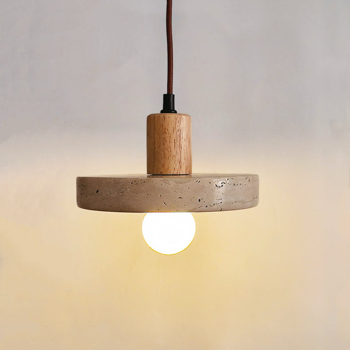 Vue rapprochée d'une suspension lumineuse en travertin et bois clair avec ampoule décorative sur fond neutre.