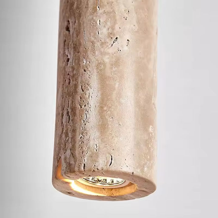 Détail d’une suspension tube en travertin, au style minéral et contemporain avec lumière chaude intégrée
