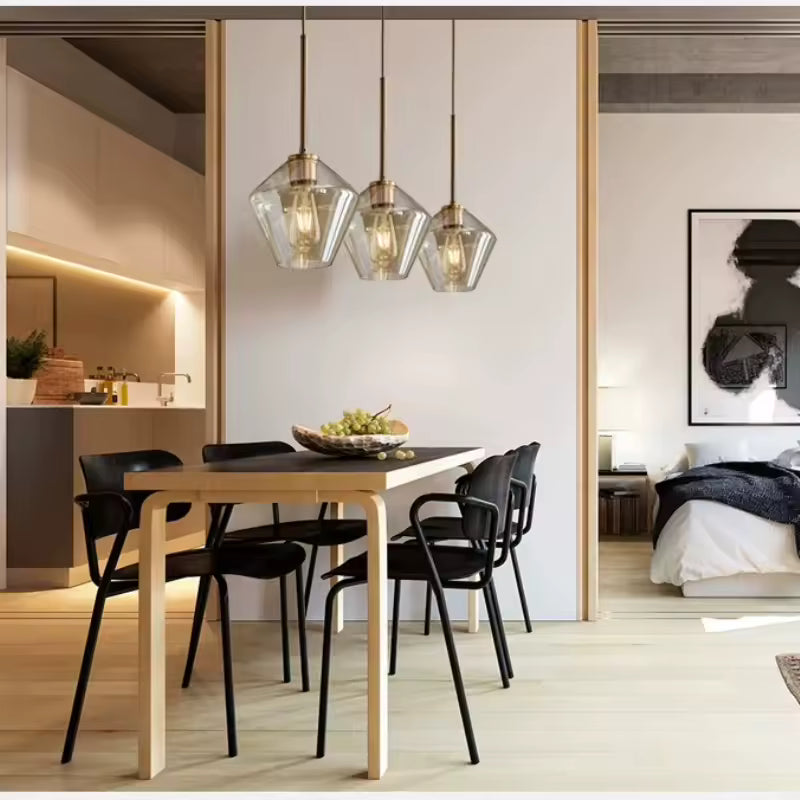 Suspension triple en verre géométrique et laiton au-dessus d’une table, dans une salle à manger moderne et épurée