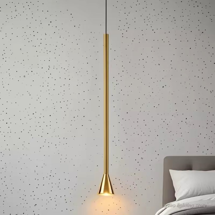 Fine suspension dorée en métal au profil vertical, avec embout trompette et allure design dans une chambre contemporaine