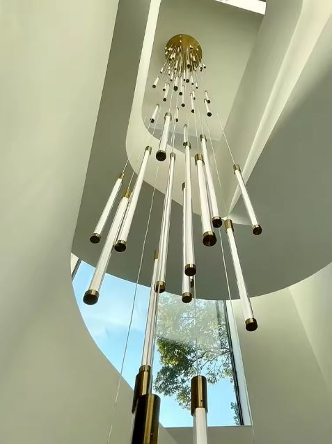 Suspension tube design pour plafond très haut, idéale dans un intérieur contemporain aux lignes organiques et lumineuses.
