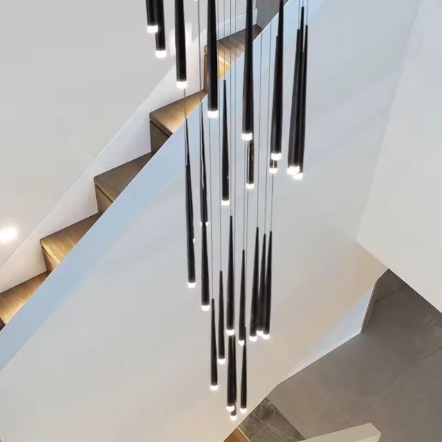 Suspension tube design noire LED suspendue dans cage d’escalier bois et blanc, parfaite pour un intérieur minimaliste et lumineux.