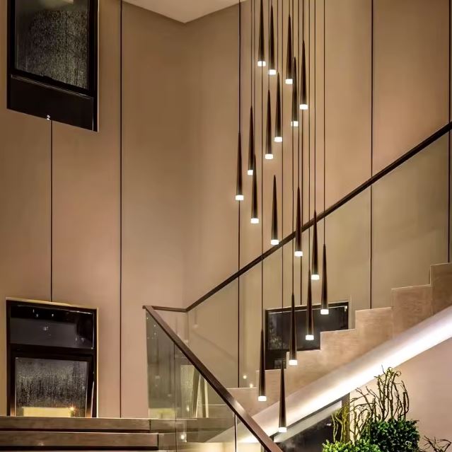 Suspension tube design noire LED pour escalier à grande hauteur sous plafond, parfaite avec garde-corps en verre et déco épurée.