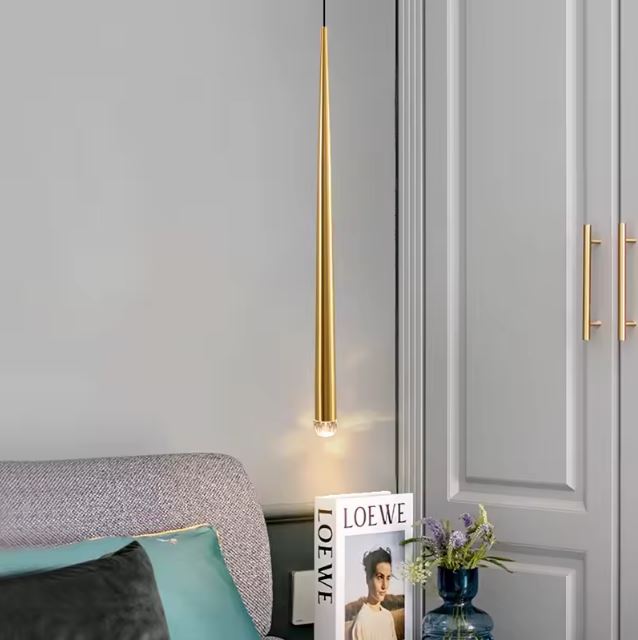 Suspension tube doré minimaliste installée dans une chambre pour un éclairage d'accentuation élégant.