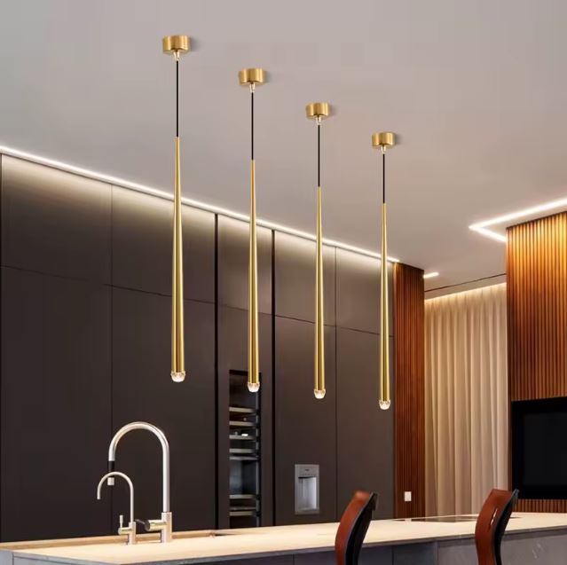 Suspension tube doré installée en série au-dessus d'un îlot de cuisine pour une ambiance moderne et raffinée.