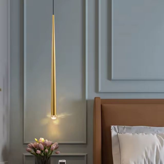 Suspension tube doré utilisée comme lampe de chevet, idéale pour une décoration minimaliste et élégante.