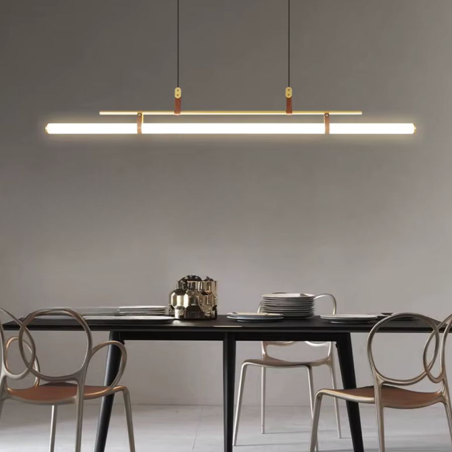 Ligne LED suspendue à structure dorée et attaches en cuir, mise en scène au-dessus d’une table au design épuré