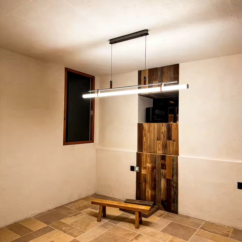 Suspension tube néon à structure en métal noir avec attaches en cuir, éclairant un intérieur contemporain aux accents de bois naturel