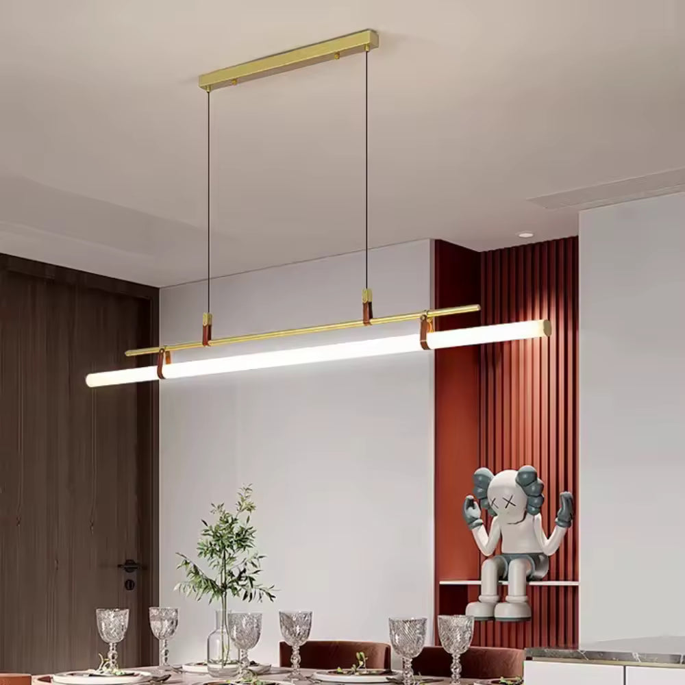 Suspension tube néon dorée avec tube led et attaches en cuir, mise en valeur au-dessus d’une table dans un décor contemporain