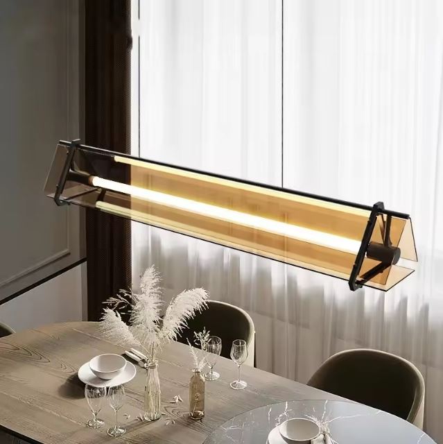 Suspension tube néon design en verre et métal suspendue au-dessus d'une table moderne dans une salle à manger lumineuse.