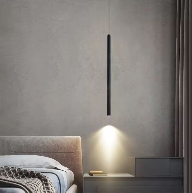 Suspension tube noir suspendue, offrant une lumière douce et chaleureuse pour une chambre moderne et minimaliste.