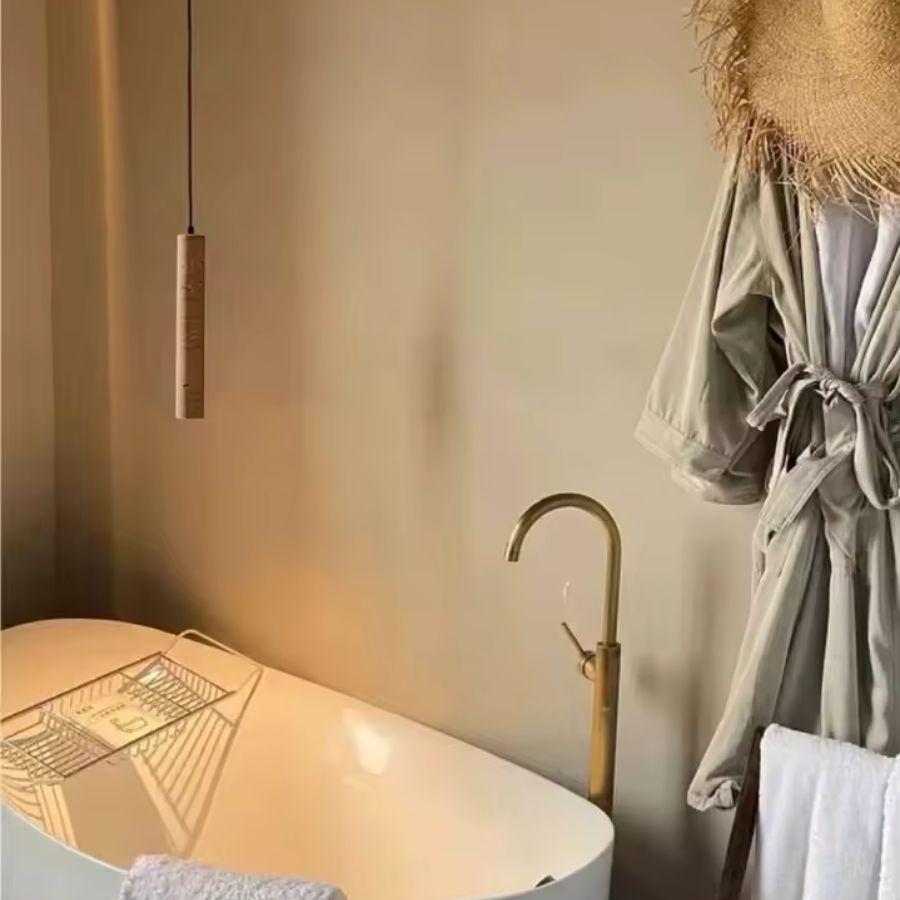 Suspension tube en travertin près d’une baignoire dans une salle de bain au style organique et chaleureux