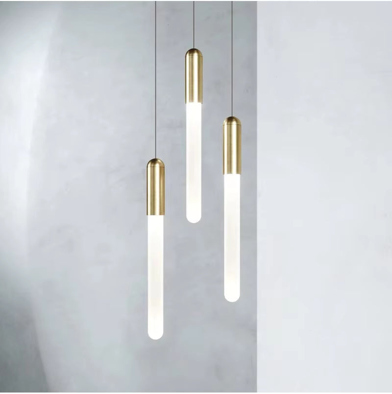 Trois diffuseurs lumineux verticaux à finition dorée composent une suspension contemporaine au style épuré