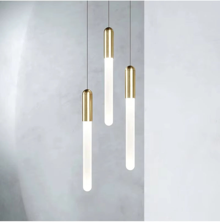 Trois diffuseurs lumineux verticaux à finition dorée composent une suspension contemporaine au style épuré