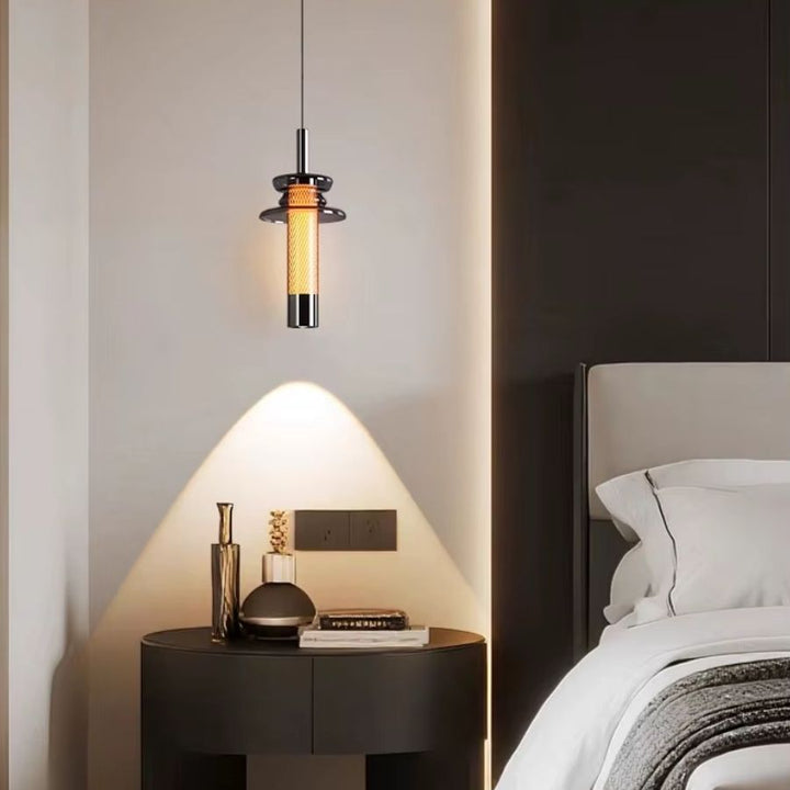 Au-dessus du chevet, ce luminaire tubulaire en verre fumé diffuse une lumière chaude dans une chambre contemporaine
