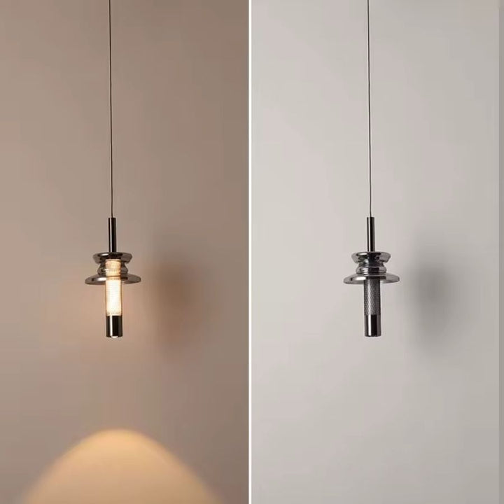 Allumée puis éteinte, cette suspension tubulaire en verre fumé révèle un éclairage chaud au design industriel