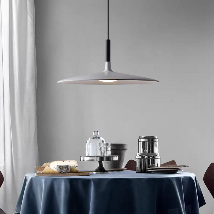 Suspension UFO blanche élégante installée dans une pièce lumineuse avec nappe bleue.