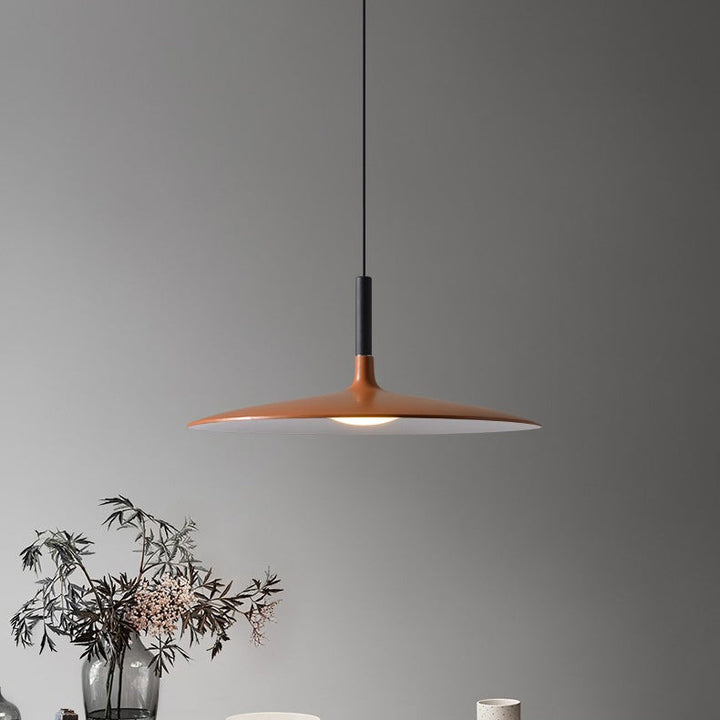Ambiance feutrée avec suspension UFO diffusant une lumière douce sur une table sombre.