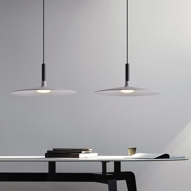 Suspension UFO noire installée dans un espace de travail ou salle à manger contemporaine.