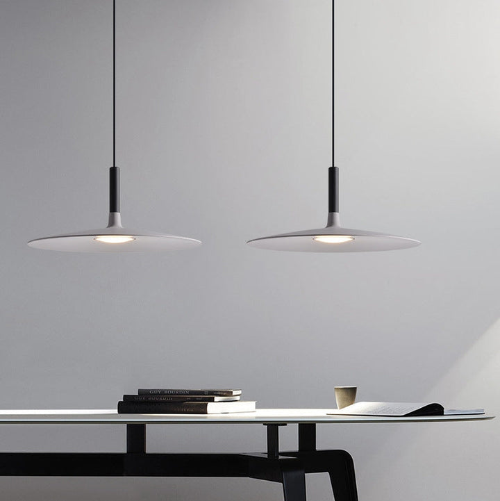 Suspension UFO noire installée dans un espace de travail ou salle à manger contemporaine.
