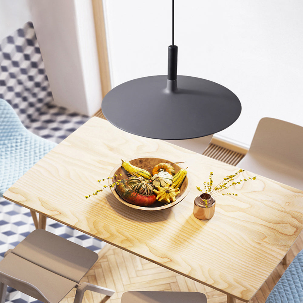 Suspension UFO noire suspendue au-dessus d'une table en bois clair avec déco florale.