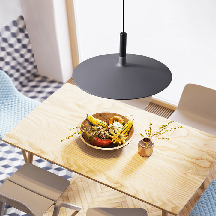 Suspension UFO noire suspendue au-dessus d'une table en bois clair avec déco florale.