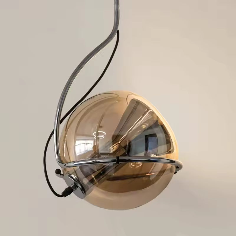 Gros plan sur une suspension en verre ambré cerclée de chrome, au design orbital et futuriste