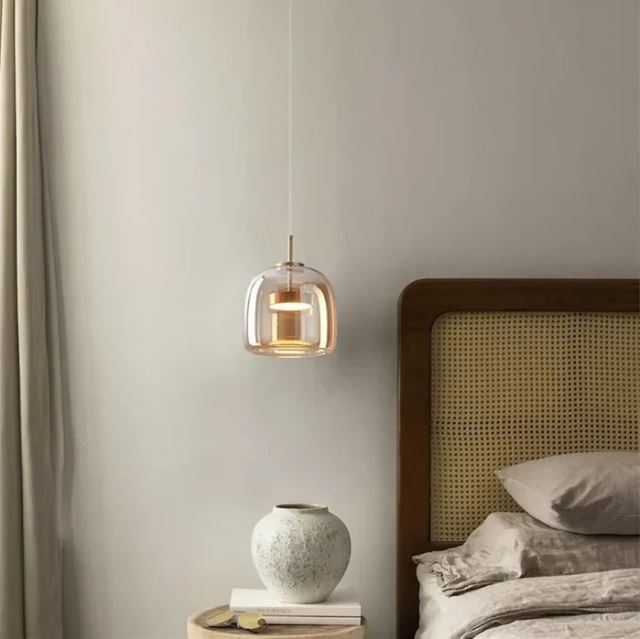 Suspension verre ambré suspendue au-dessus d'une table de chevet, idéale pour une chambre moderne et élégante.