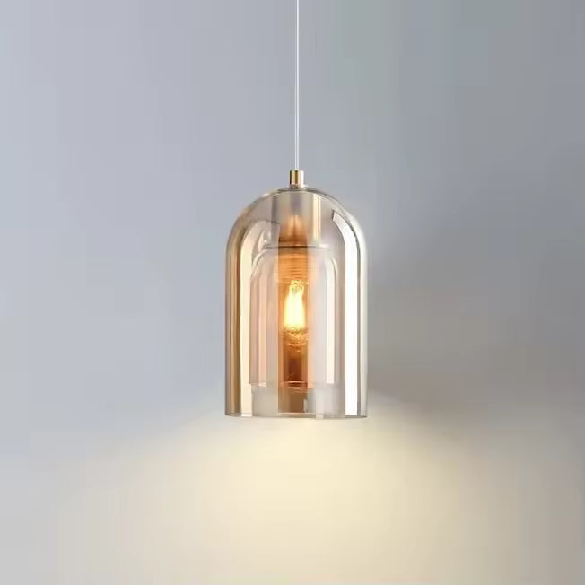 Suspension en verre ambré aux courbes arrondies, diffusant une lumière chaleureuse dans un esprit moderne et épuré.