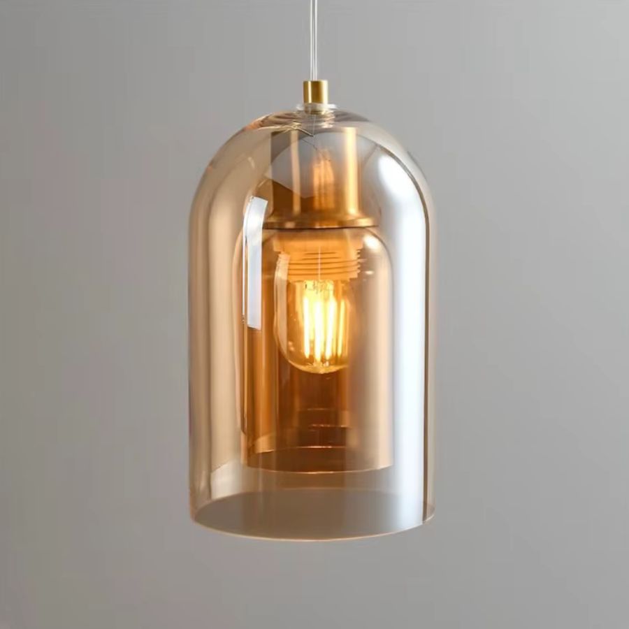 Vue rapprochée d'une suspension en verre ambré à double enveloppe, avec ampoule apparente et détails dorés au style rétro chic.