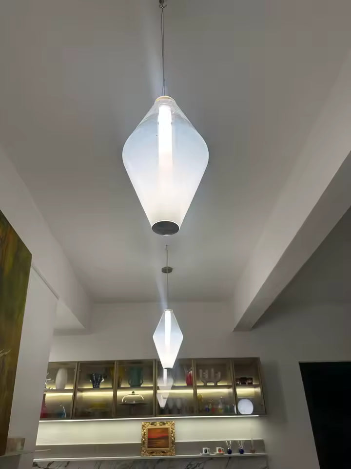 Luminaire en verre blanc aux lignes sculpturales, suspendu dans un intérieur contemporain avec éclairage vertical intégré