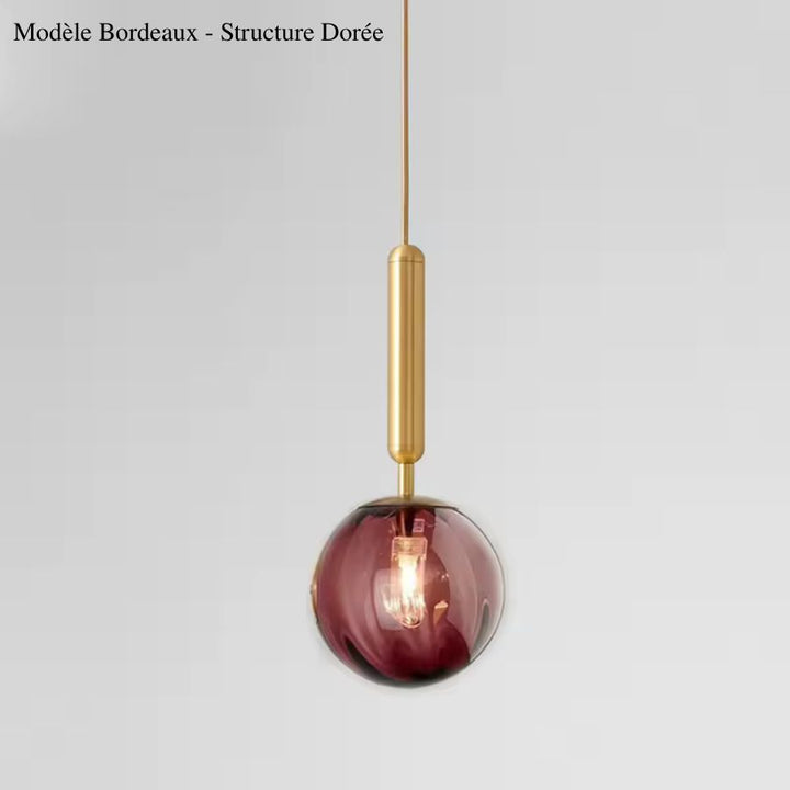 Alliance d’un globe en verre bordeaux et d’une tige dorée élancée pour une suspension raffinée aux accents rétro chic