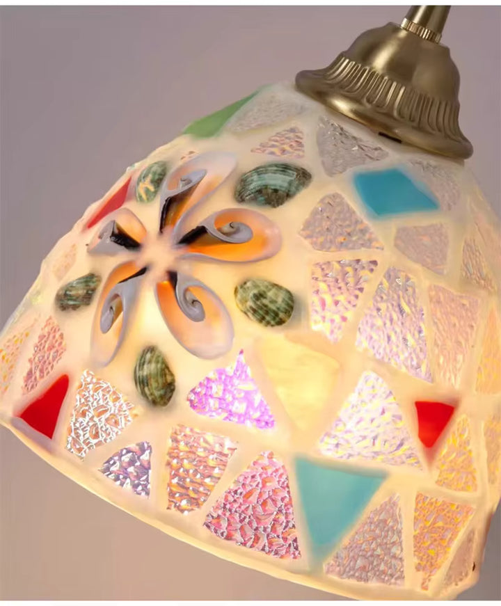 Gros plan d’une suspension en verre coloré façonné façon mosaïque, au style bohème avec détails inspirés des coquillages