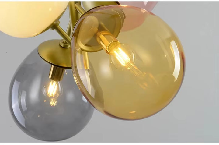 Détail des globes en verre ambre et fumé d’une suspension rétro aux ampoules apparentes et finitions dorées
