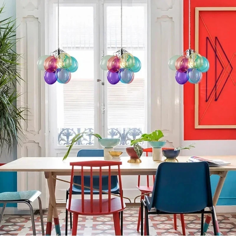 Suspension japandi en verre translucide multicolore illuminant une grande salle à manger épurée.