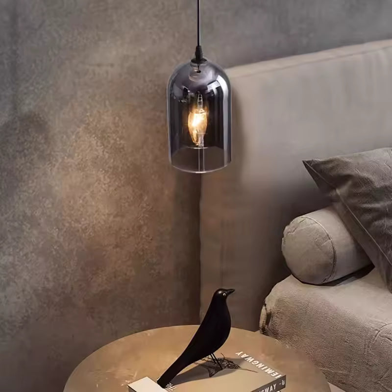 Près d'un lit beige, une suspension en verre fumé à ampoule apparente crée une ambiance intimiste au style contemporain chic.