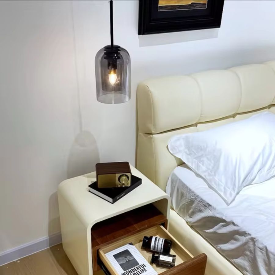 Près d'un lit à tête capitonnée, une suspension en verre fumé en forme de cloche apporte une touche contemporaine raffinée.