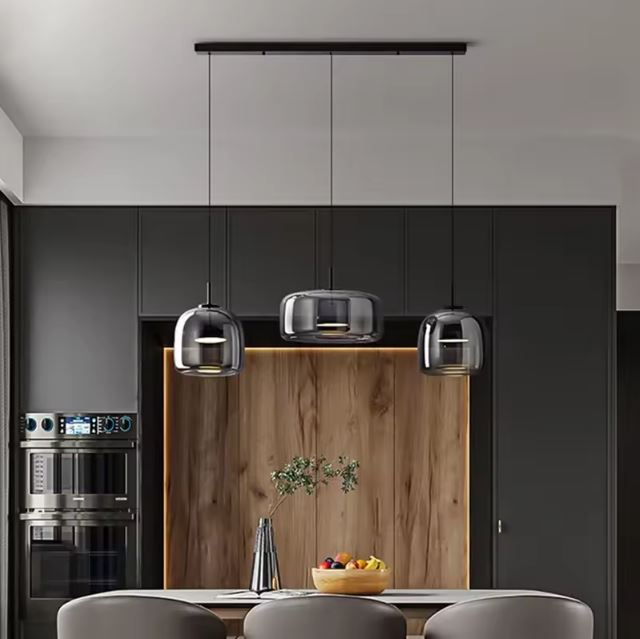 Suspension verre fumé gris en triple alignement, parfaite pour sublimer une cuisine moderne et scandinave avec îlot et finitions bois noir.