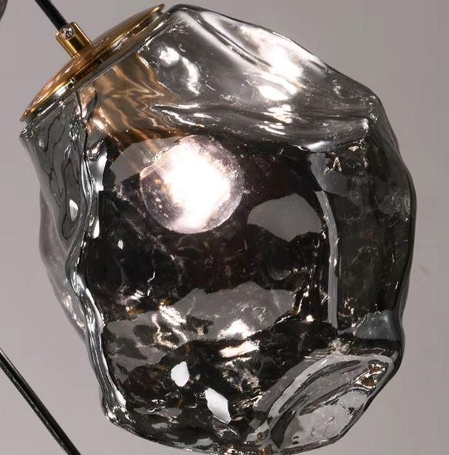 Détail de suspension en verre fumé aux formes organiques, luminaire d’inspiration minérale au caractère artisanal raffiné.