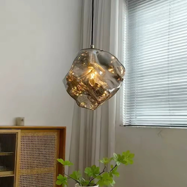 Forme minérale en verre fumé pour cette suspension design, aux reflets chaleureux et à l’allure organique contemporaine