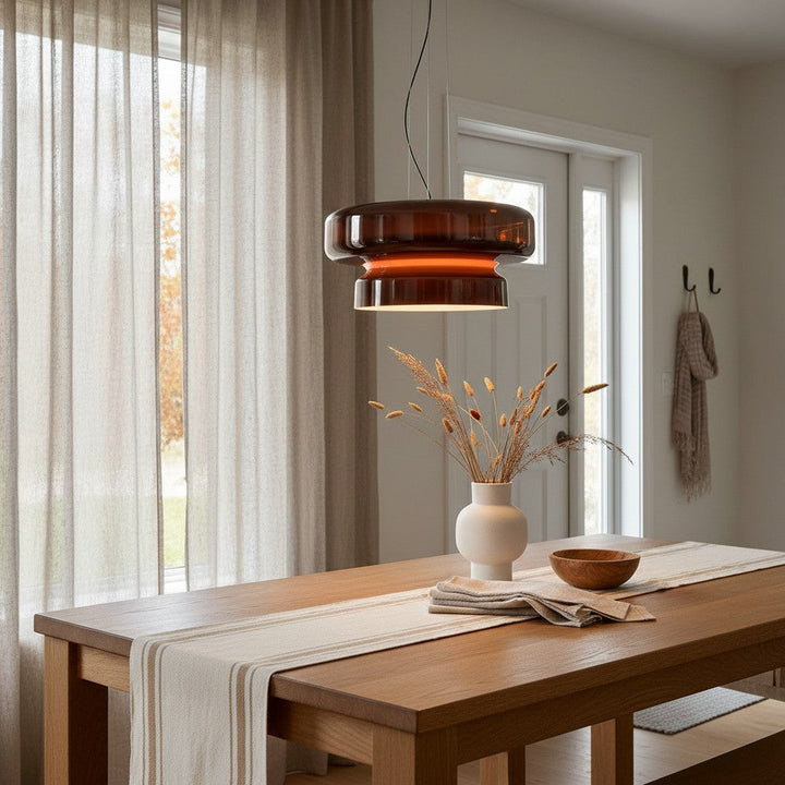 Suspension en verre fumé rouge brun dans une salle à manger épurée et lumineuse aux accents boisés.